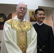 Father Michael B. McGarry, Paulist president, stands with Dat Q. Tran after Mr. Tran's final promises with the Paulists.