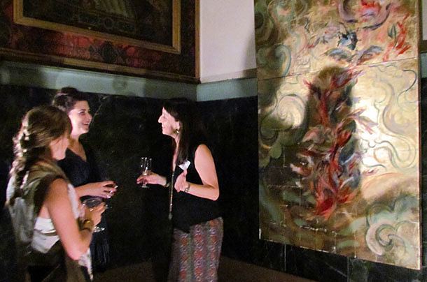 Artist Christina Batch-Lee (right) speaks with Heather Burkman (left) and Emily Tidwell in front of her artwork titled "Beating of Wings," oil and metal leaf on canvas, 4x8 feet.