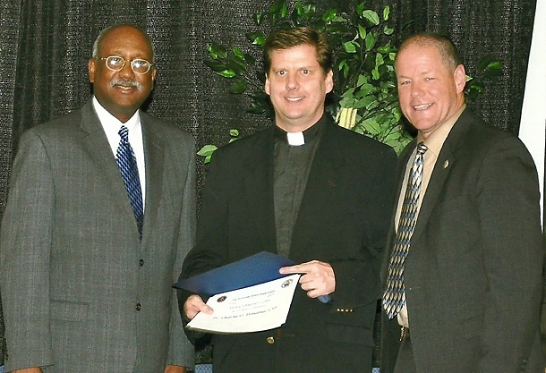 Knoxville, Tenn., Mayor Daniel T. Brown (left) and Police Chief David Rausch (right) pose with Father Charlie Donahue, CSP, after his swearing in as a police chaplain.