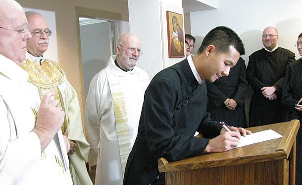 Dat Q. Tran, CSP, signs the contract stating he is a Paulist for life. Vocations Director Father Paul Huesing, CSP (back right), Paulist President Father Michael B. McGarry and Novice Director Father John J. Behnke, CSP, look on.