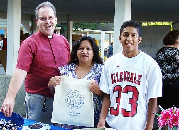 Father Don Andrie, CSP, and Maria and Zander Espinoza man the St. Luke University Parish table at the Back to School Fair at Grand Valley State University in Allendale, Mich..