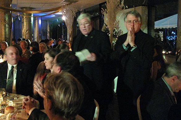 Father Tom Post (left) leads grace as Father Gregory Apparcel, CSP (right), and the 250 attendees of the Santa Susanna's 60th Annual Charity Serata ljoin in.