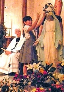 A statue of Mary is crowned at St. Austin Church in Austin as Pastor Father Charles Kullmann, CSP, looks on. 