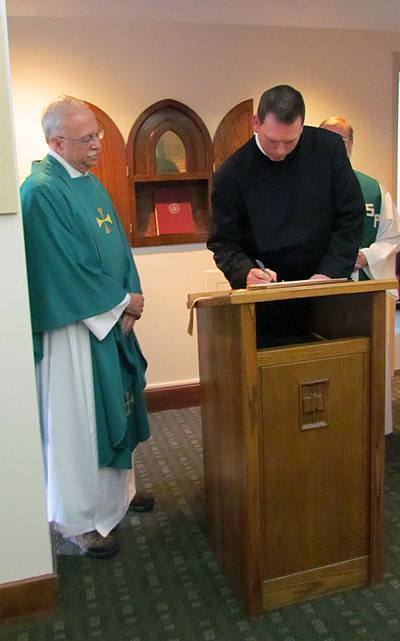 Steven Petroff, CSP, signs the contract in which he promises to live by the Paulist constitution for the next 12 months after making  his first promise with the Paulist Fathers. Paulist President Father Michael McGarry (left) looks on.
