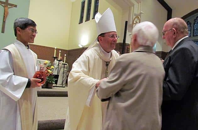 Father Ivan Tou, CSP, pastor of St. Lawrence Church and Newman Center in Minneapolis (left), and Bishop Lee Piche of the Archdiocese of St. Paul-Minneapolis (right) accept the gifts of bread and wine from parishioners during the parish's 125th anniversary