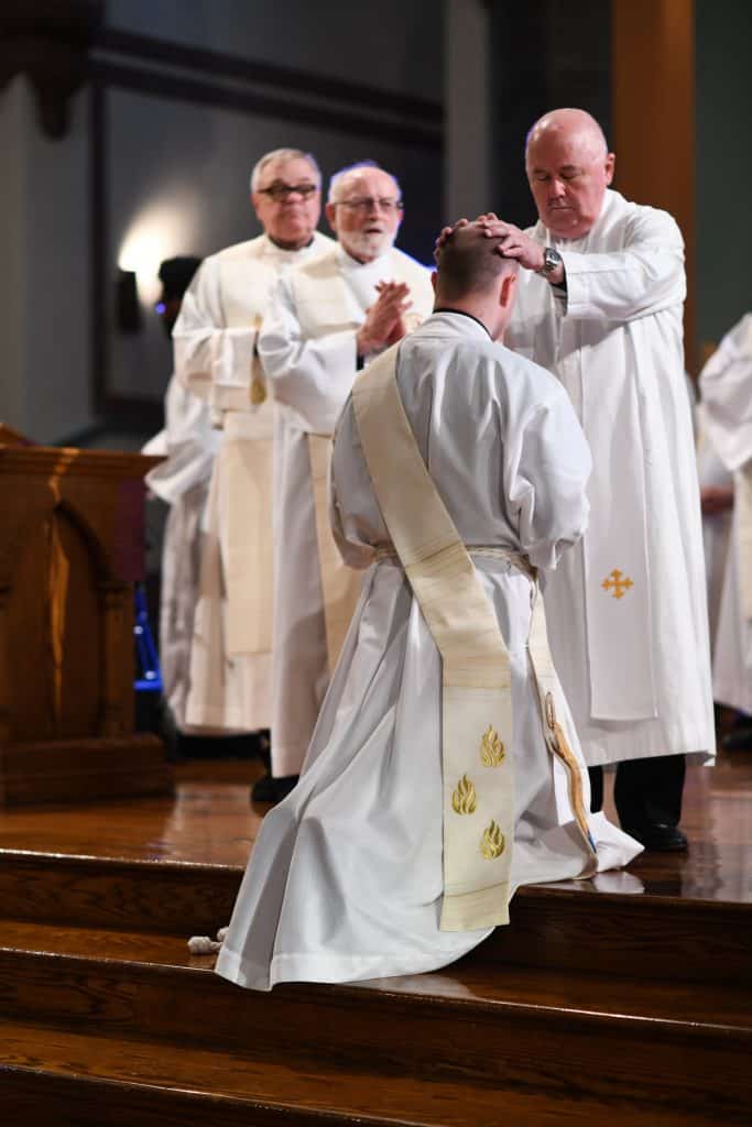 Paulist Fr. Tim Tighe prays over Paulist Fr. Mike Hennessy at the Mass in May, 2018, at which Fr. Mike was ordained a priest.